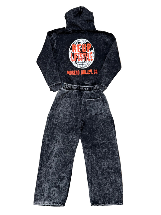 Black acid-wash hoodie and pants set with visible branding on a concrete surface